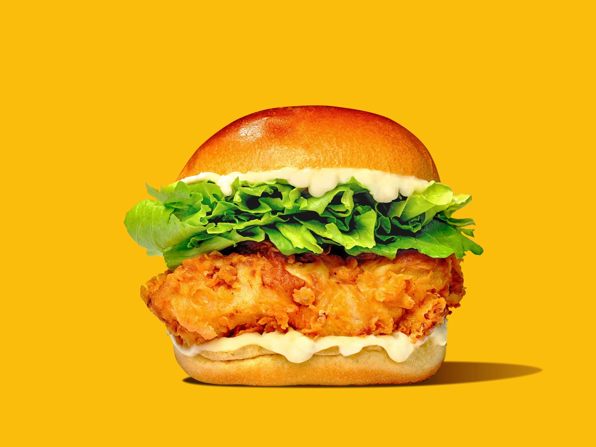 Crispy chicken burger on a vivid yellow background