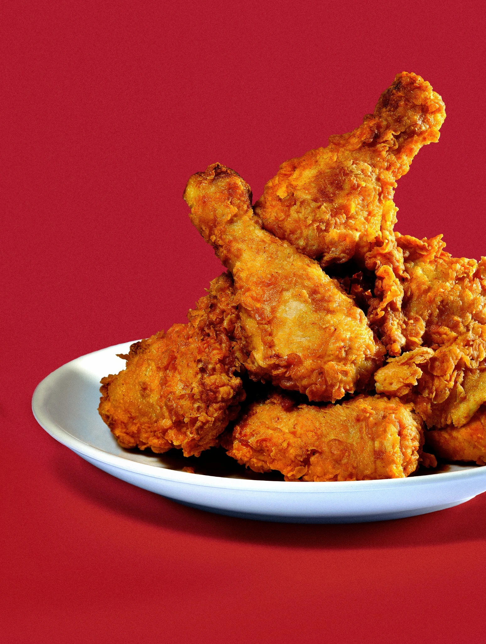 Crispy fried chicken stacked against a deep red background